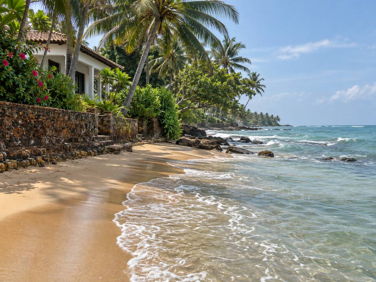 Private beach area with wet sand, hibiscus and a low laterite wall at 10 am